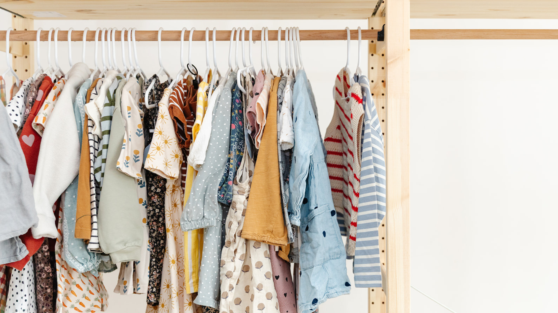 A rack of preloved children's clothing on white hangers